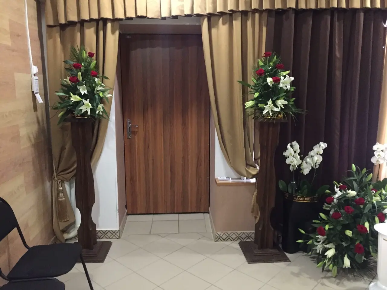 Вход в зал прощания с цветочными композициями и драпировкой